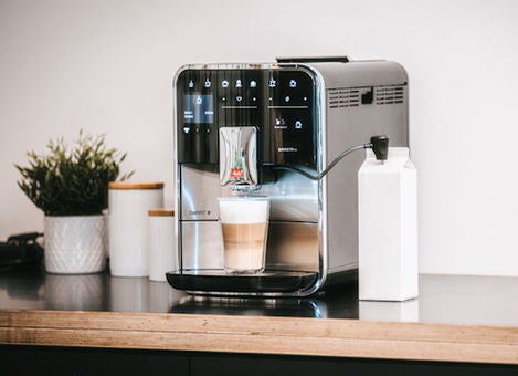 Melitta Barista TS Smart avec un latte macchiato posé sur une table